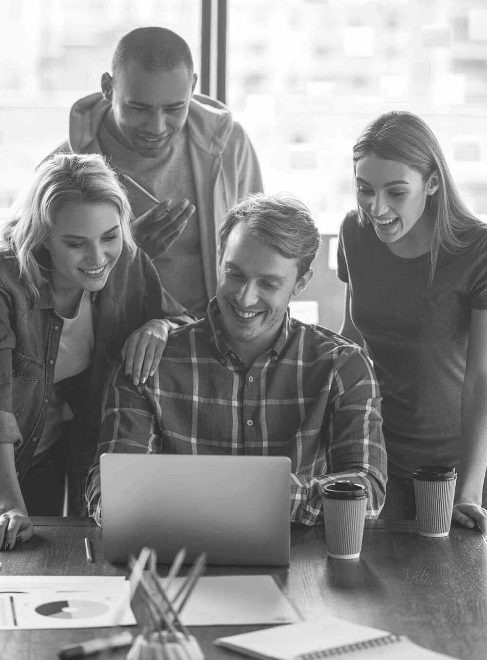 Two women and one man looking over the shoulder of a co-worker showing the project on his laptop